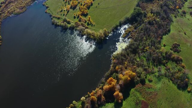An aerial shot of the Shihan Juraktau mountain and surrounding landscape in the South Ural region of Russia during the autumn season. The footage captures the vibrant fall foliage, a calm body of wate