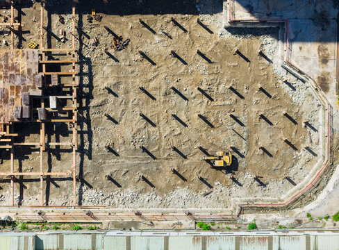 New construction site with excavator steel beams and shadows