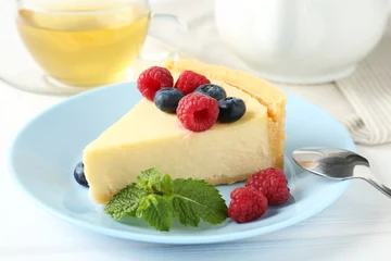 Fototapete Zu Essen Piece of delicious cheesecake with fresh berries and mint served on white wooden table, closeup  © New Africa