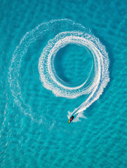 A jet ski moves swiftly in a circular pattern, leaving behind a beautiful wake in the turquoise waters of a tropical beach on a sunny day. Generative AI.
