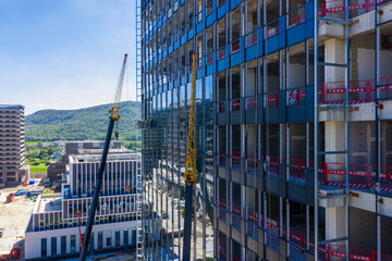 High rise building construction with cranes and glass facade