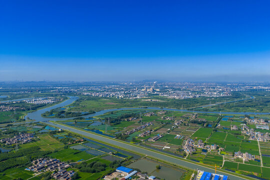 Aerial view of rural farmland with river and city skyline
