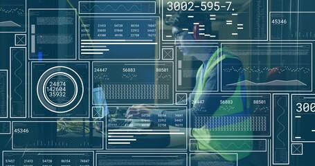 Monitoring technician in vest analyzing laptop data at warehouse station, data panels, copy space