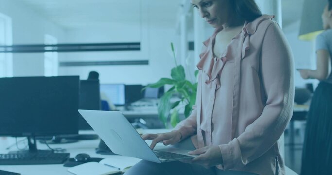 Sitting businesswoman typing on laptop on desk edge at open office, smartphone notebook, copy space