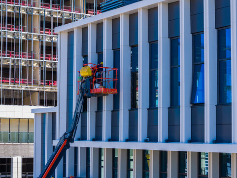 Construction workers on lift working on modern office building facade