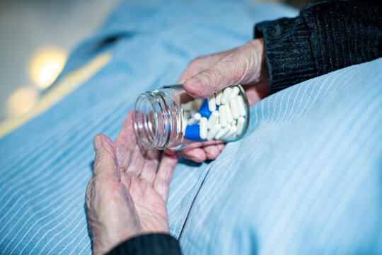 Elderly hands holding a jar of capsules