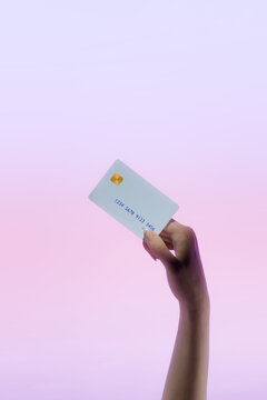 Hand holding Debit Credit Card Against a Pastel Background