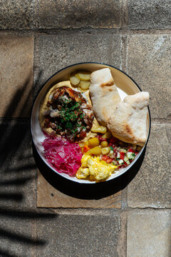 Hummus bowl with grilled meat, vegetables, and pita bread