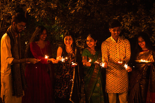 Group of Indian friends with sparkles celebrating Diwali night.