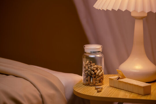 A bedside scene featuring capsules, a pill organizer