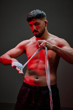 Male boxer preparing for training in a dramatic lighting setting