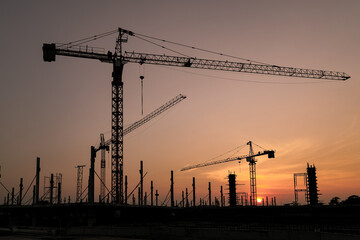 New construction site with crane and mechanical equipments on sunset background.
