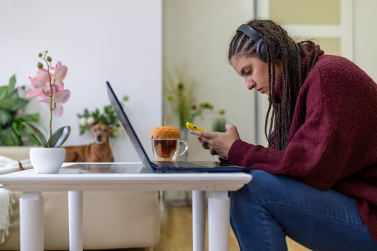 A woman in headphones editing video on digital devices for social networks.
The girl creating content on computer and smartphone at home. Video blogging and internet multimedia.