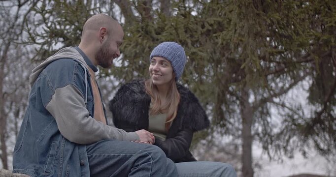 Joyful young couple sharing an intimate conversation during a tranquil autumn day in the park.