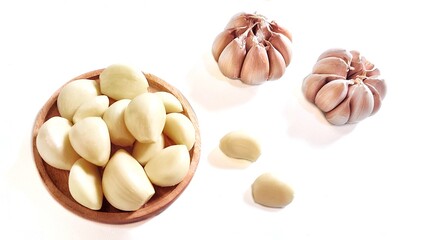 Garlic cloves and garlic bulb in a wooden plate. Isolated on white background with copy space. Clipping Path. Perfect for design element, food recipe or any commercial usage.
