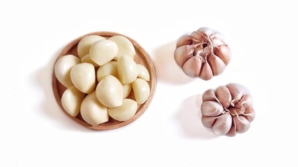 Garlic cloves and garlic bulb in a wooden plate. Isolated on white background with copy space. Clipping Path. Perfect for design element, food recipe or any commercial usage. Top view. Flat lay.