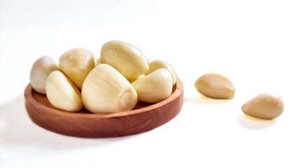Garlic cloves and garlic bulb in a wooden plate. Isolated on white background with copy space. Clipping Path. Perfect for design element, food recipe or any commercial usage. Front view.