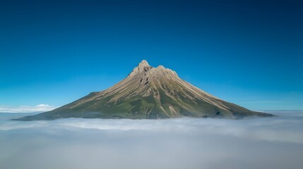 Majestic mountain peak rising above the clouds under a clear blue sky, capturing the breathtaking natural beauty of the high alpine landscape in peaceful and serene atmosphere.