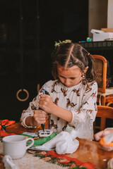 A portrait of a little girl decorating a Christmas gingerbread cookie with icing during a children's holiday workshop. Preparing for Christmas and New Year's. Children party.