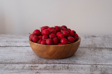 ripe hawthorn fruits in wooden plate on table.