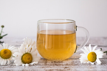 Chamomile tea with fresh daisies on a wooden table, an inviting setting for relaxation.