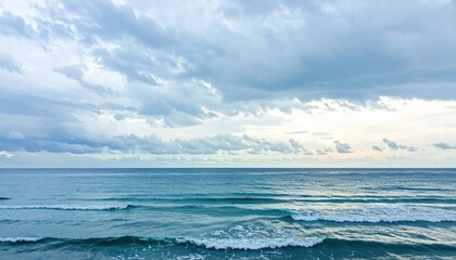 Fototapeta premium Serene coastal landscape during twilight, with gentle waves lapping against the shore under cloudy skies