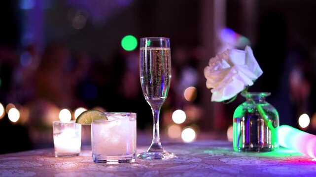 slow motion of drinks on a table during a party wedding reception with people dancing in the background 