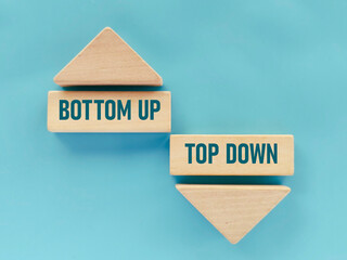 Bottom Up and Top Down Concept on Wooden Blocks with Arrows Representing Conflicting Business Strategies and Methodologies © MohamadFaizal