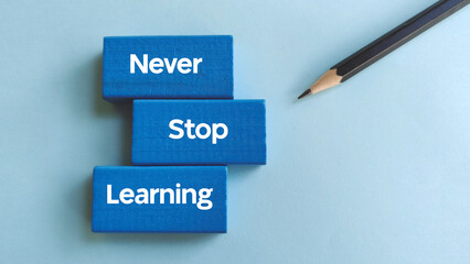 Never Stop Learning Text on Blue Blocks with Pencil Representing Continuous Education, Growth, and Motivation
