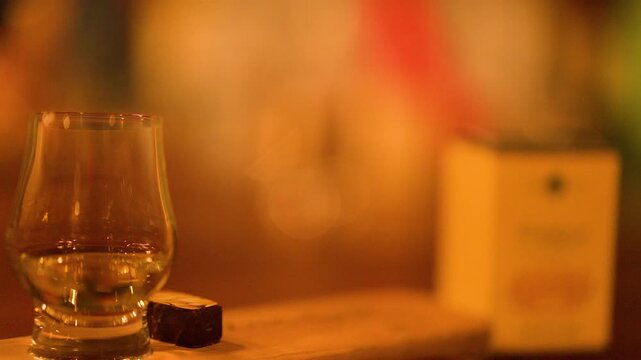 Hand Lifting Whisky Glass in Cozy Scottish Bar Setting
