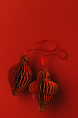 Festive Red Paper Christmas Ornaments,  hanging red flashlight or lantern, honeycomb scandinavian decor on red background, minimal monochrome photo, festive holiday mood, top view, copy space