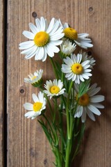 Obraz premium A charming bouquet of delicate white daisies with sunny yellow centers, artfully arranged against a rustic wooden backdrop.