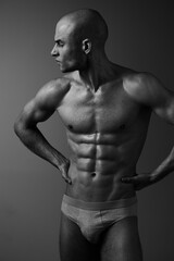 Fototapeta premium Athletic man posing confidently, showcasing a muscular physique in a striking black and white portrait. This image exudes strength and determination in a minimalist style.