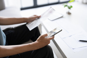 Man calculate finances home pay bills taxes on mobile phone financial at home.