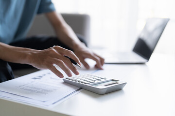 Man Managing Personal Finances Budget Household Expenses and Calculating Taxes with Calculator on the Table at Home.