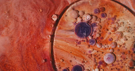 Oil fluid. Color bubbles. Defocused orange purple glitter water sparkling round ink texture circle on abstract acrylic background.