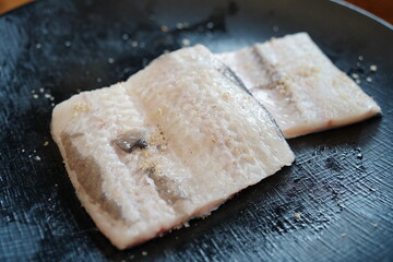 Fresh Raw Eel Fillets on a Black Plate, Ready for Cooking