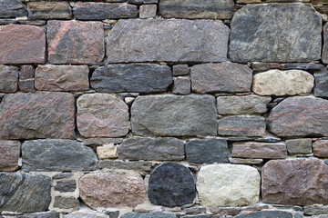 Fieldstone wall constructed from naturally occurring irregularly shaped stones displaying a rustic and natural aesthetic horizontal orientation