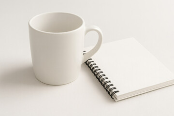 White Coffee Mug and Spiral Notebook on White Desk