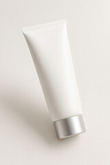 Blank White Cosmetic Tube with Silver Cap on Beige Background