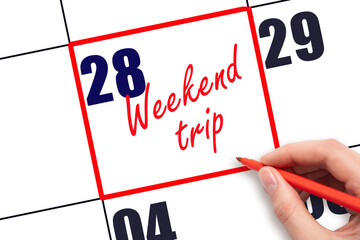 28 th day of the month. Hand writing Weekend trip reminder and drawing red frame on calendar with red pen on white background. Business concept. Travel concept. Planning and scheduling.