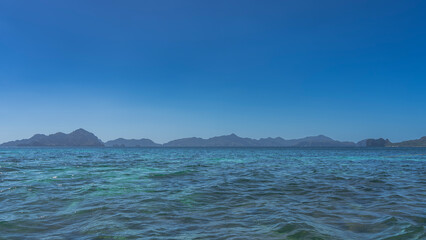 Beautiful minimalistic seascape. Ripples on the surface of a calm turquoise ocean. Mountains on the horizon. Clear blue sky. Copy space. Philippines. Palawan.
