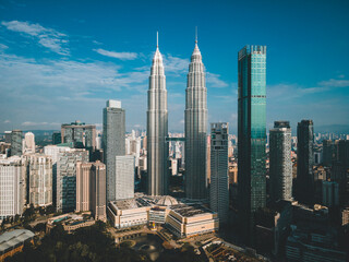 Obraz premium A KLCC drone photo shows a bird's-eye view of Kuala Lumpur's cityscape. The Petronas Twin Towers soar above KLCC Park, surrounded by a cluster of modern skyscrapers.