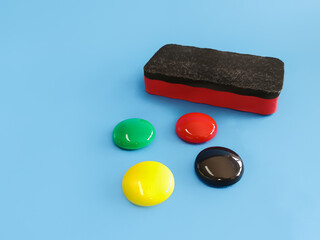 Colorful magnetic buttons isolated on blue. Office and school supplies for notes, reminders, and organization. Bright, simple, and practical stationery concept