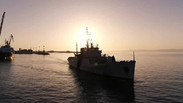 Naval Ship Sailing Into the Sunset Over a Calm Sea