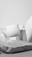 Elegant 3D render of a floating white cosmetic jar among natural stones. Minimalistic product mockup design for skincare, beauty branding, or luxury cosmetic presentation visuals.