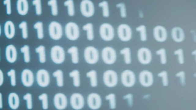 Close-up view of binary code symbols, representing digital data and information technology, on a screen with a blurred background.