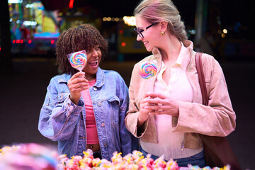 Diverse friends laughing buying candies at carnival