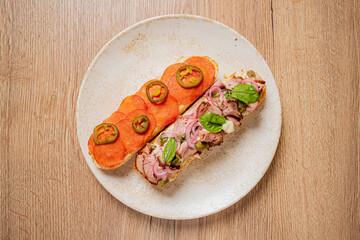 Tasty sandwich stacked with meat, fresh veggies, and spices on a ceramic plate