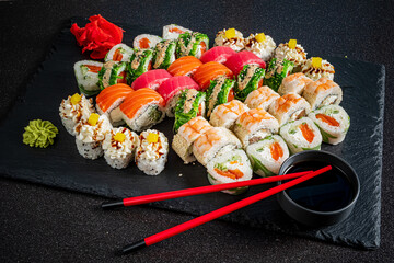 Beautifully arranged sushi rolls on a slate platter, with wasabi and soy sauce